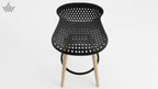 Black perforated stool with wooden legs on a white background