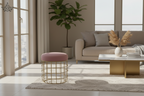 Pink cushioned stool with gold metal frame on a light background