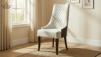 White upholstered chair with wooden legs in a room with a window and beige walls.